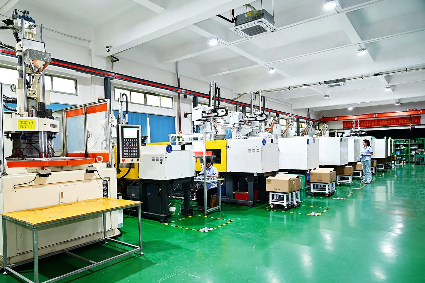 MOLDITQUICK injection molding hall — a row of presses with take-out robots running OEM production programs