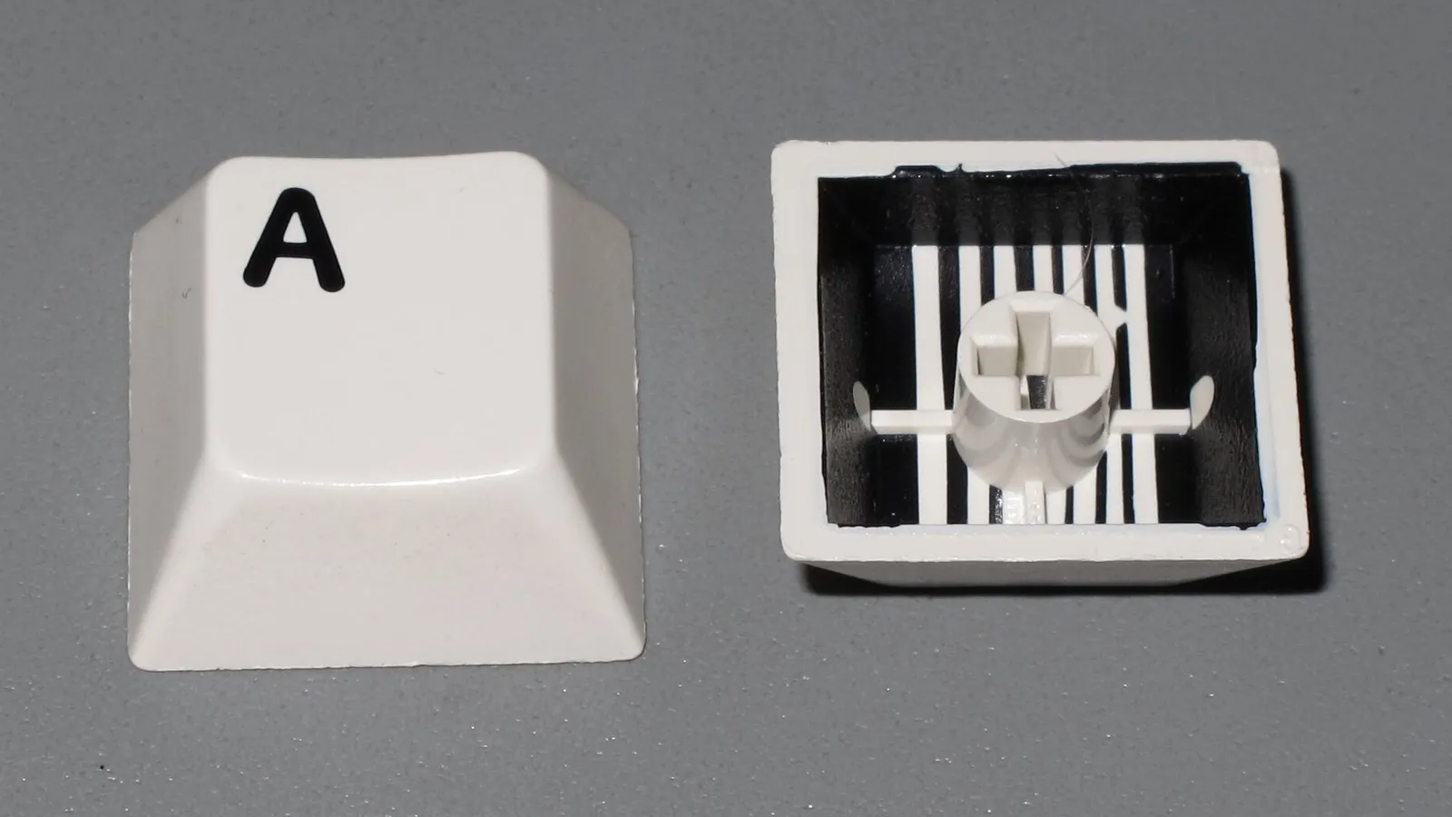 Two-shot injection molded button keycaps shown top face and underside with stem boss and ribs